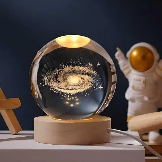 Decorative galaxy sphere on a wooden base with an astronaut figurine in the background.